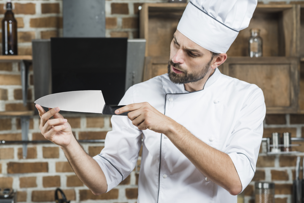 Chef checking the edge of a sharp knife in a commercial kitchen Chef checking the edge of a sharp knife in a commercial kitchen