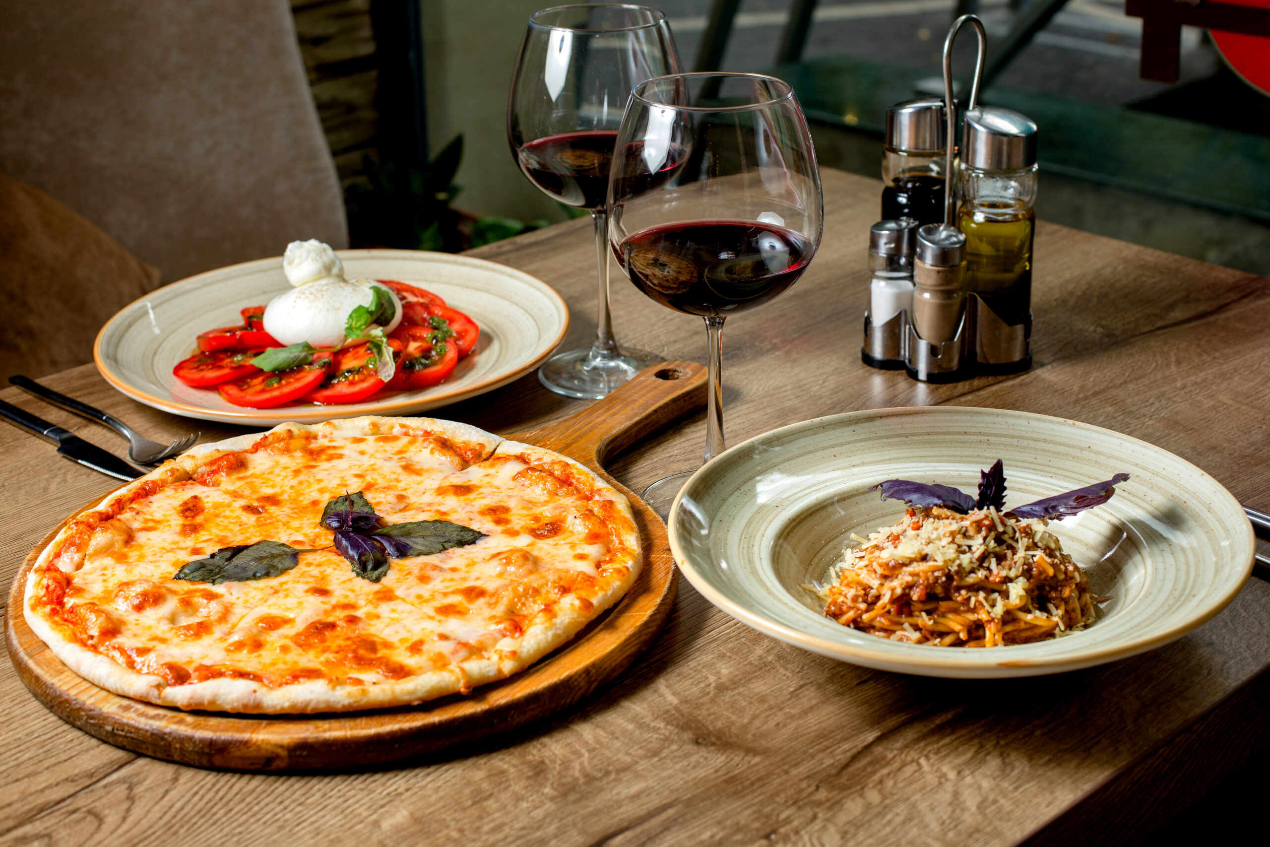 Italian dinner set with margherita pizza, pasta, salad and wine